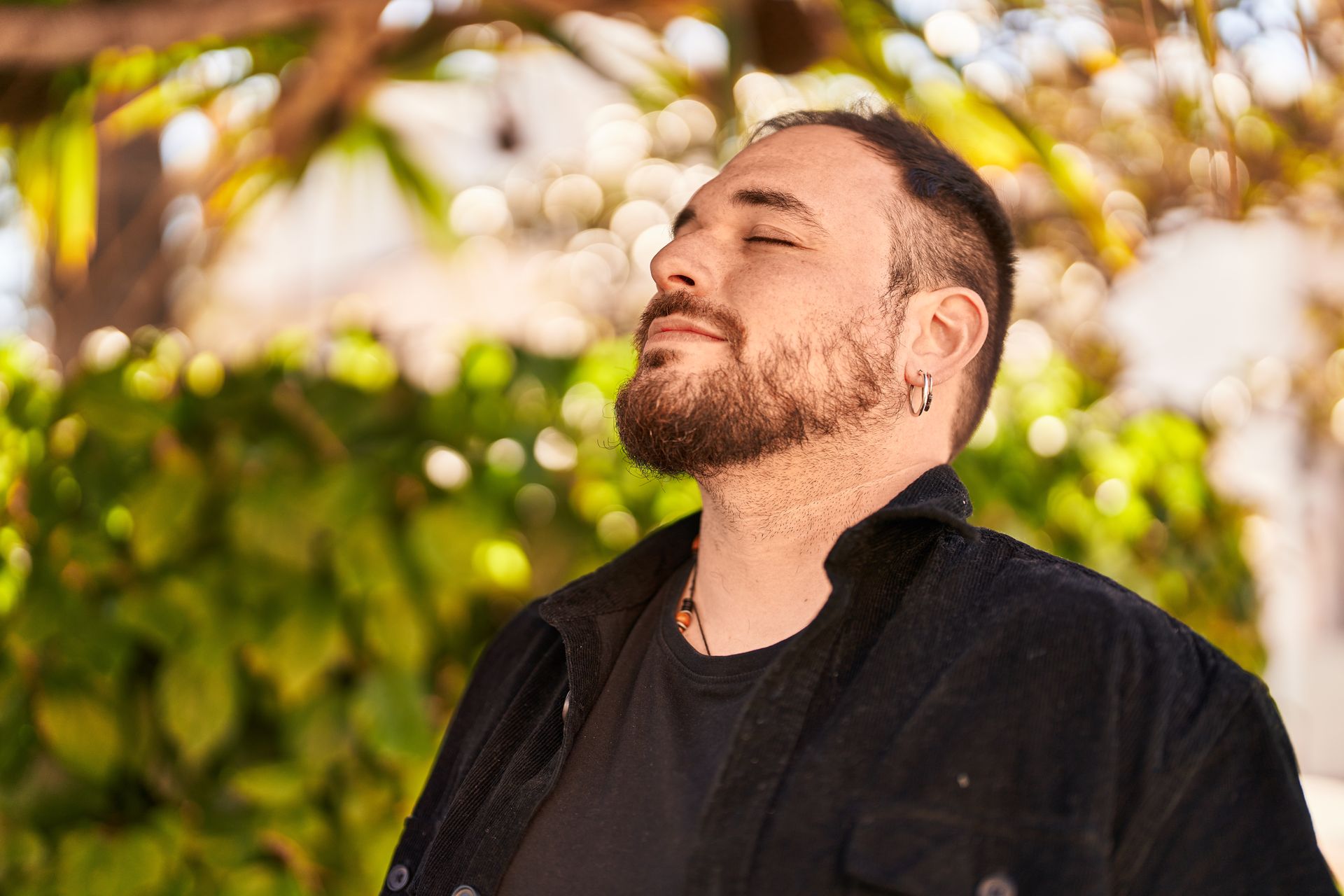 Homem ao ar livre, de olhos fechados, respirando fundo na luz do fim da tarde